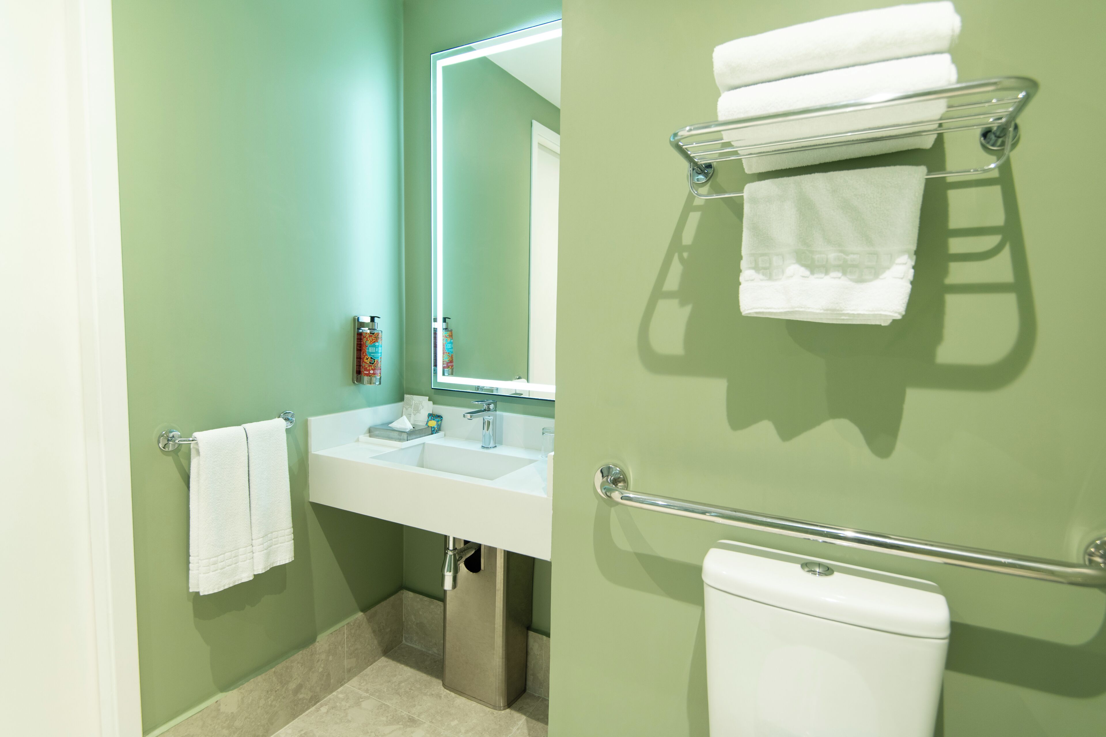 Une salle de bain équipée d’un lavabo, d’un miroir, d’un porte-serviettes et de toilettes.