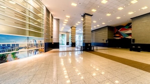 A spacious lobby with a high ceiling, reflective floor, and large windows offering a view of the cityscape. - Grand Mercure Sao Paulo Vila Olimpia (São Paulo)