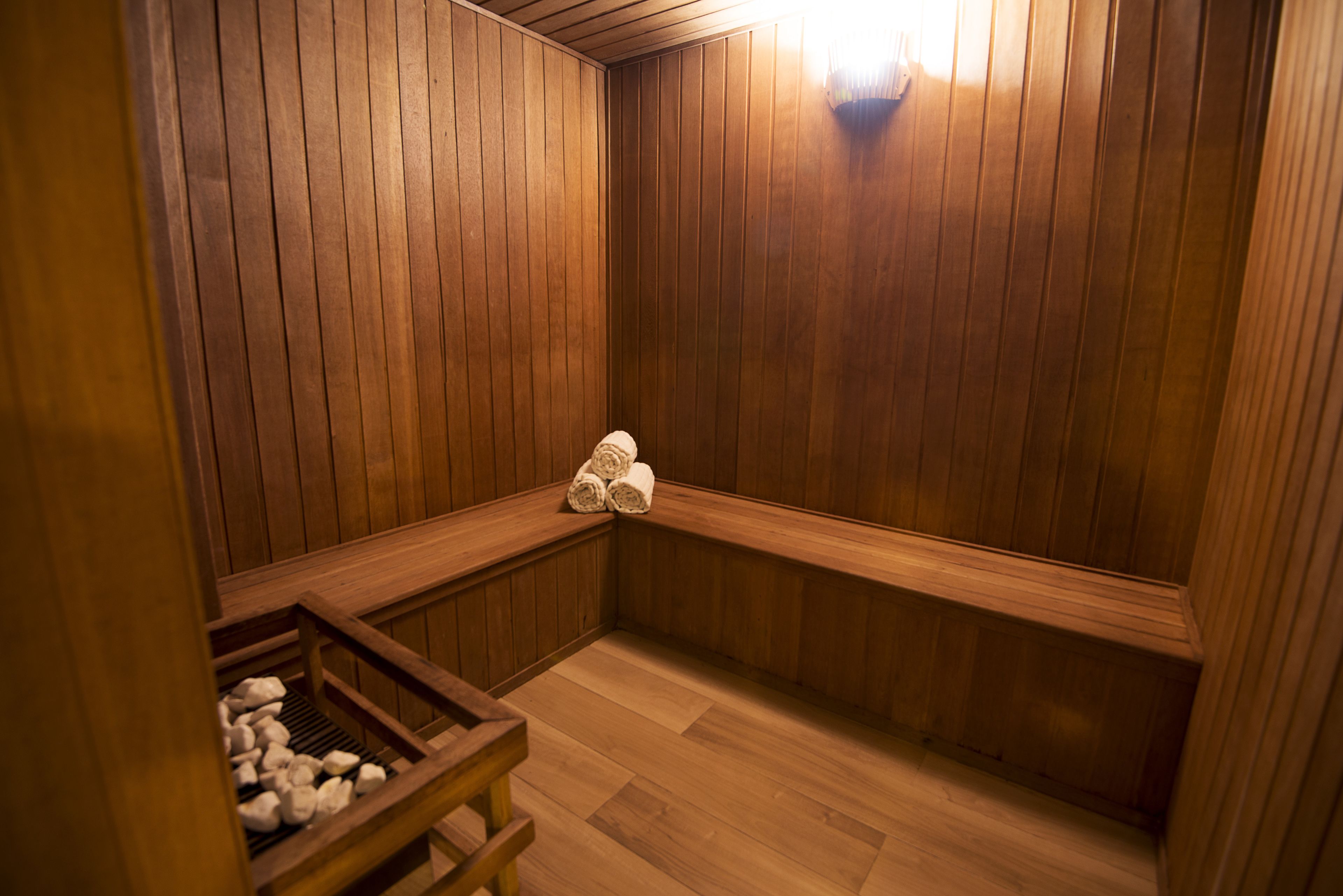 A sauna room with wooden walls, benches, and a wooden bench with towels.