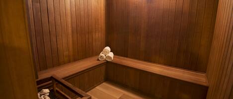 A sauna room with wooden walls, benches, and a wooden bench with towels.