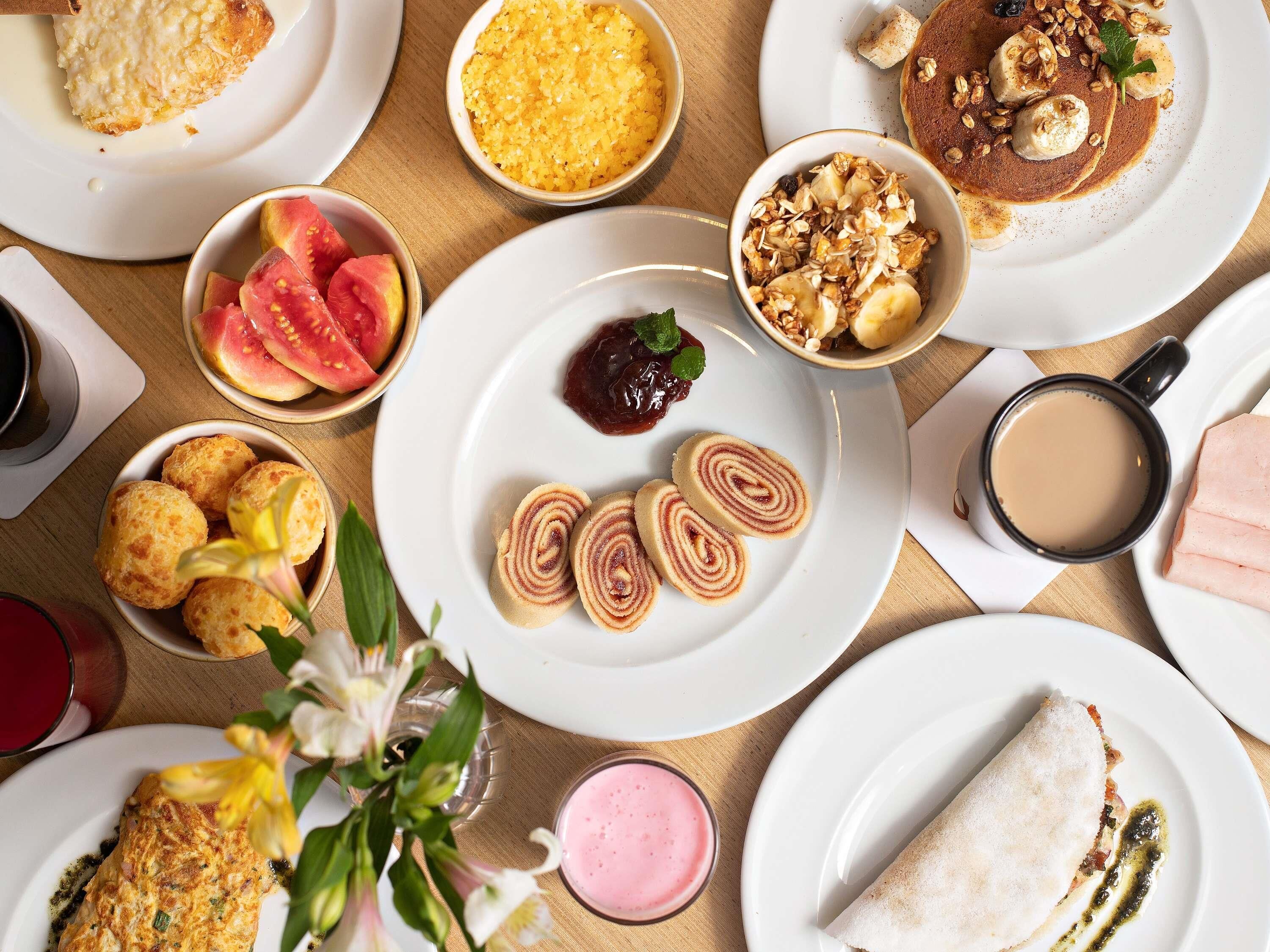 A variety of breakfast items on a table, including pancakes, fruit, and a rolled pastry.