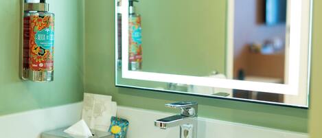 A bathroom with a mirror, a sink, and toiletries.
