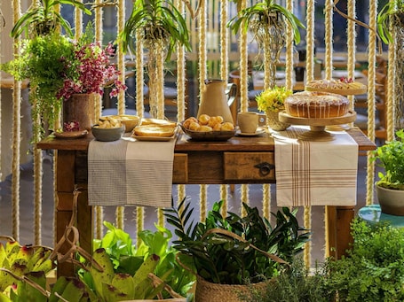 Uma mesa de madeira com diversos alimentos e plantas, com um fundo de cordas verticais.. Grand Mercure Sao Paulo Vila Olimpia