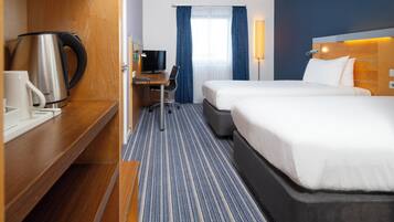 Une chambre d’hôtel avec deux lits, un bureau avec une chaise, une machine à café et un téléviseur.