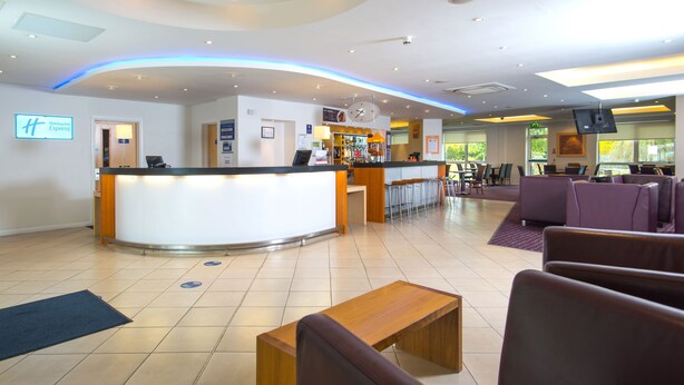 A hotel lobby with a reception desk, seating area, and a bar. - Holiday Inn Express Bedford by IHG (Bedford)