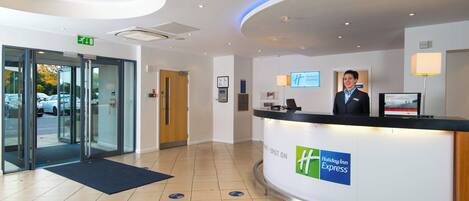 A hotel reception area with a Holiday Inn Express sign, a reception desk, and a digital screen.