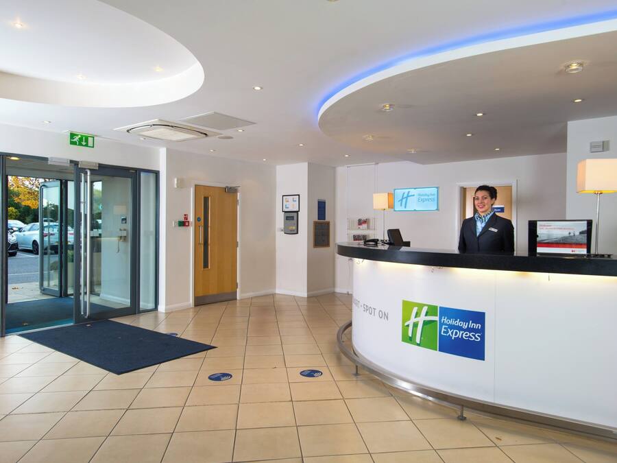 A hotel reception area with a Holiday Inn Express sign, a reception desk, and a digital screen.