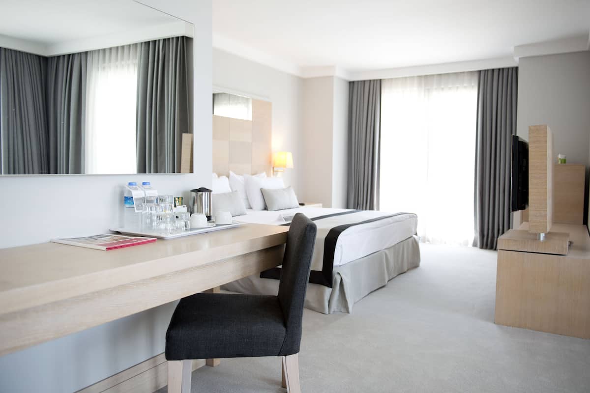 Una habitación de hotel con cama, escritorio, silla, televisor y minibar.