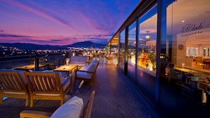 A rooftop terrace with outdoor seating and a view of the city at dusk. - Ramada Resort by Wyndham Bodrum (Bodrum)