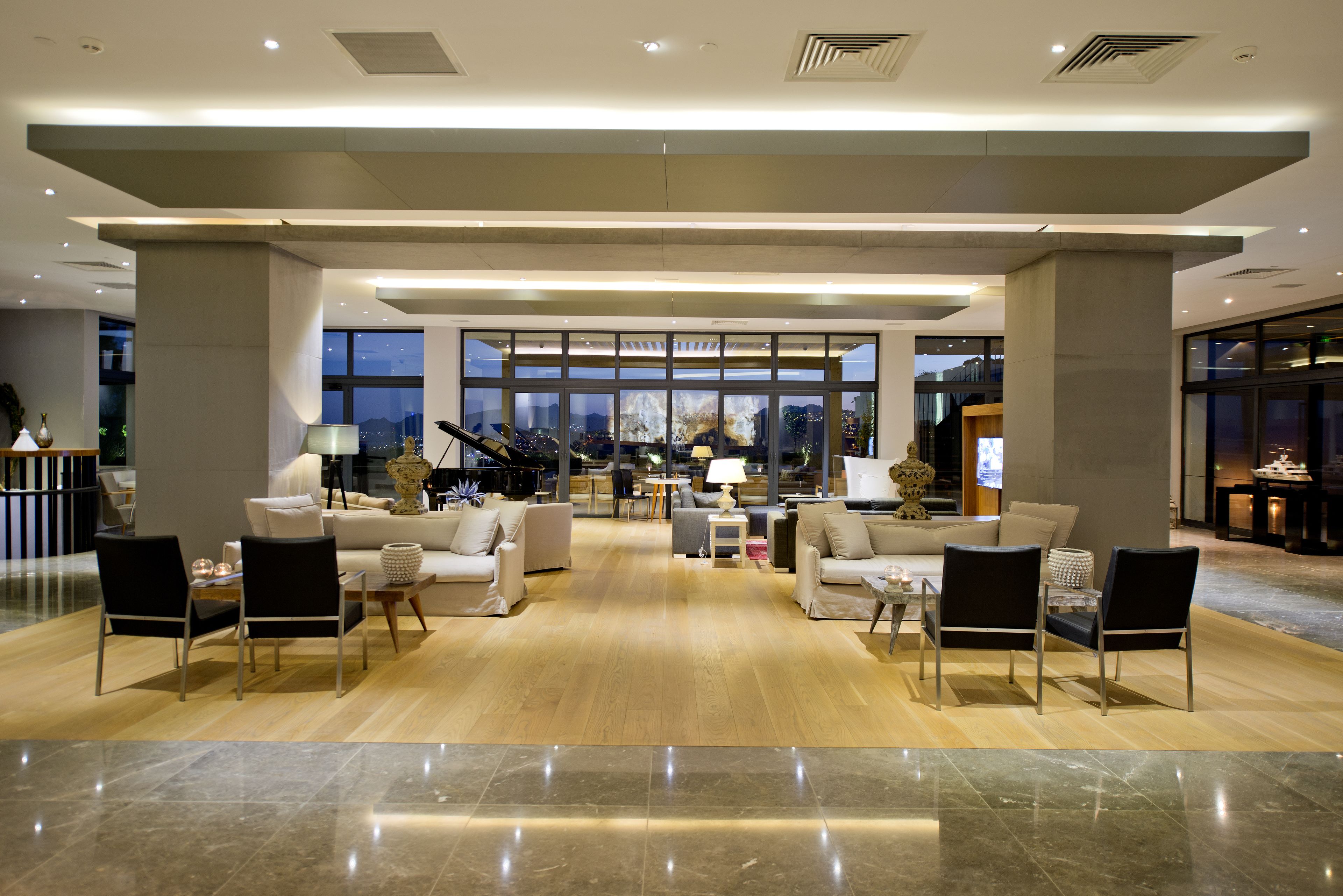 Un vestíbulo amplio con techo alto, ventanas grandes y una zona de estar central con sofás y sillones.