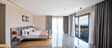 A modern hotel room with a large bed, a desk, and a balcony with curtains.