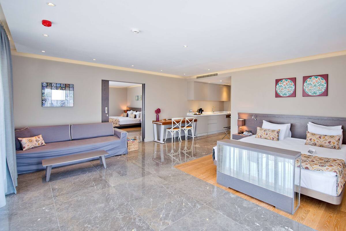 Una habitación de hotel moderna con sofá, cama, zona de comedor y cocina.