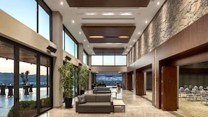 A spacious lobby with a high ceiling, large windows, and a seating area with sofas and tables. - Ramada Resort by Wyndham Bodrum (Bodrum)