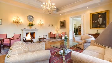 Un salón amplio con chimenea, muebles elegantes y una araña.