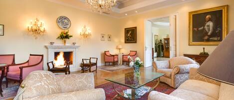 Un salón amplio con chimenea, muebles elegantes y una araña.
