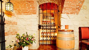 Una habitación con paredes de ladrillo, una botellera, un barril de madera y una planta en maceta.