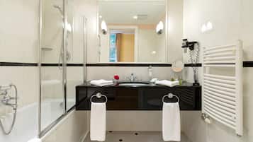 Un baño moderno con ducha envuelta en vidrio, lavamanos con encimera negra y radiador blanco.