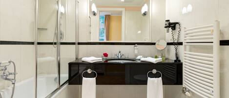 A modern bathroom with a glass-enclosed shower, a black countertop sink, and a white radiator.