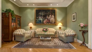 Una sala de estar con dos sofás a rayas, una mesa de centro de vidrio, un cuadro grande enmarcado y un mueble de madera.