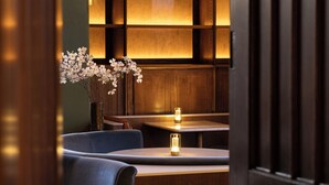 A dimly lit interior with wooden paneling, a seating area with cushioned chairs, and a vase with white flowers. - JA Mar Hall Scotland (Bishopton)