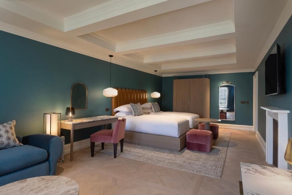 Une chambre à coucher comprenant un lit, un bureau, une chaise et un pouf.