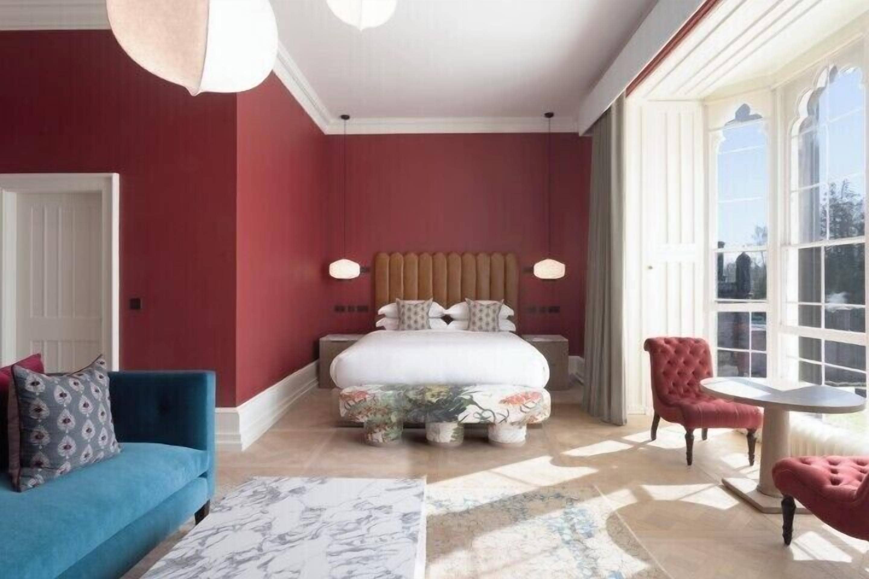 A bedroom with a bed, a blue sofa, a round table, and a red chair.