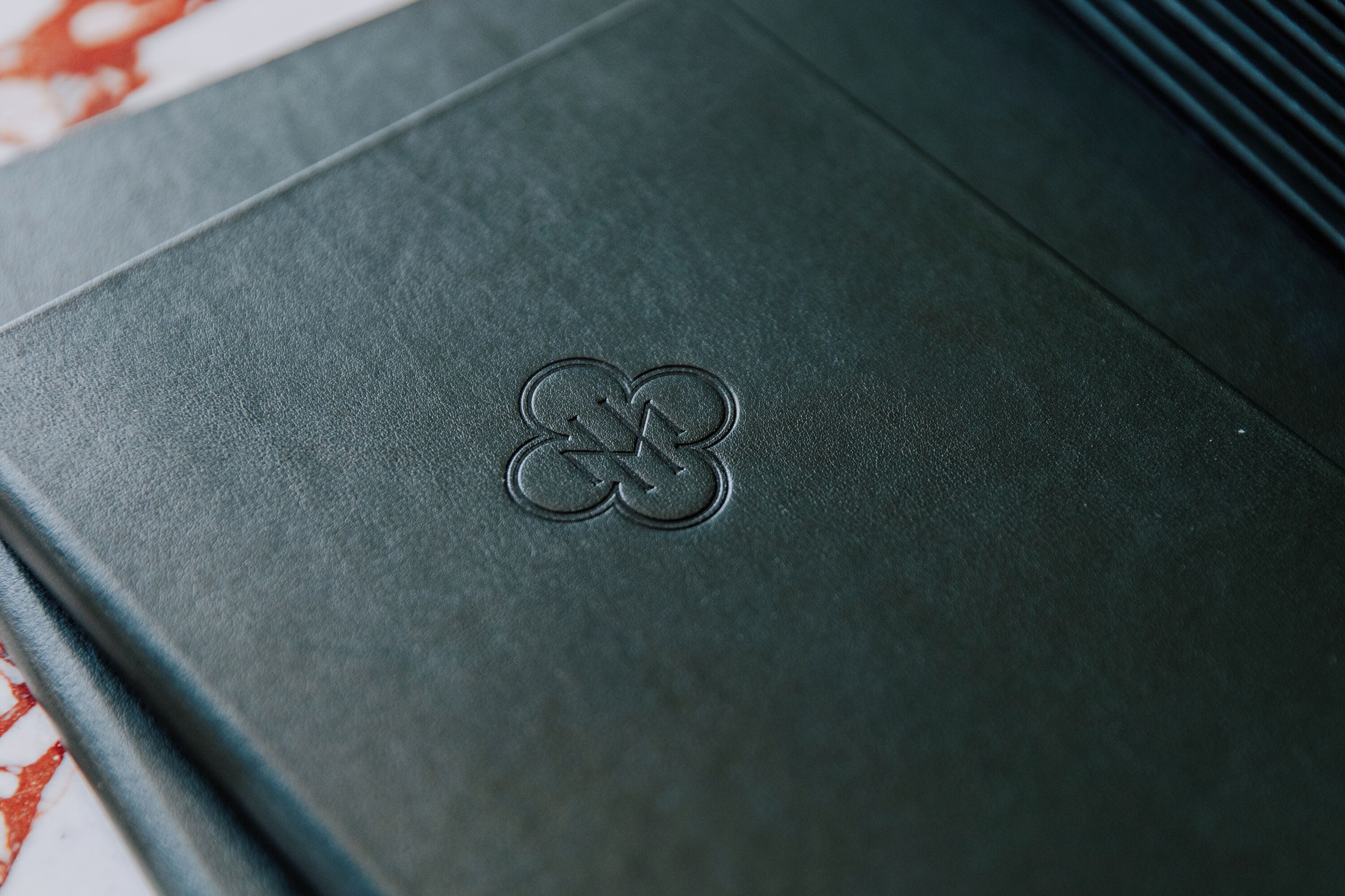 A dark-colored folder with a logo embossed on the front.