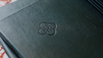 A dark-colored folder with a logo embossed on the front.