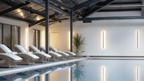 A modern indoor pool area with lounge chairs and a potted plant. - JA Mar Hall Scotland (Bishopton)