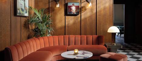 Ein moderner Lounge-Bereich mit einer gebogenen Couch, einem runden Couchtisch und einem Schachbrettmuster-Boden.