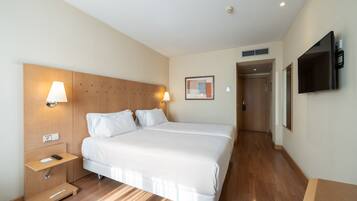 Une chambre d’hôtel avec un grand lit, des tables de chevet, une télévision et une porte donnant sur une autre pièce.