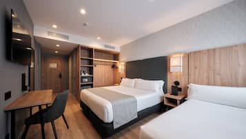 A modern hotel room with a large bed, a desk, and a wardrobe.