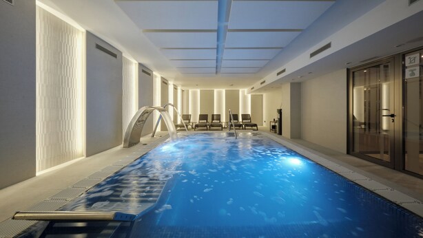 Une piscine intérieure à l’eau claire, entourée de chaises longues et dotée d’une porte vitrée sur un de ses côtés.
