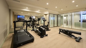 Une salle de sport équipée de tapis de course, de vélos elliptiques et d’un banc de musculation.