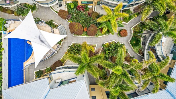 An aerial view of a hotel with a central courtyard, multiple balconies, and a pool. - The Cove Yamba (Yamba)
