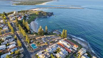 An aerial view of a coastal residential area with houses, a beach, and a marina.