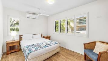 A bedroom with a bed, a nightstand, a chair, and a ceiling fan.