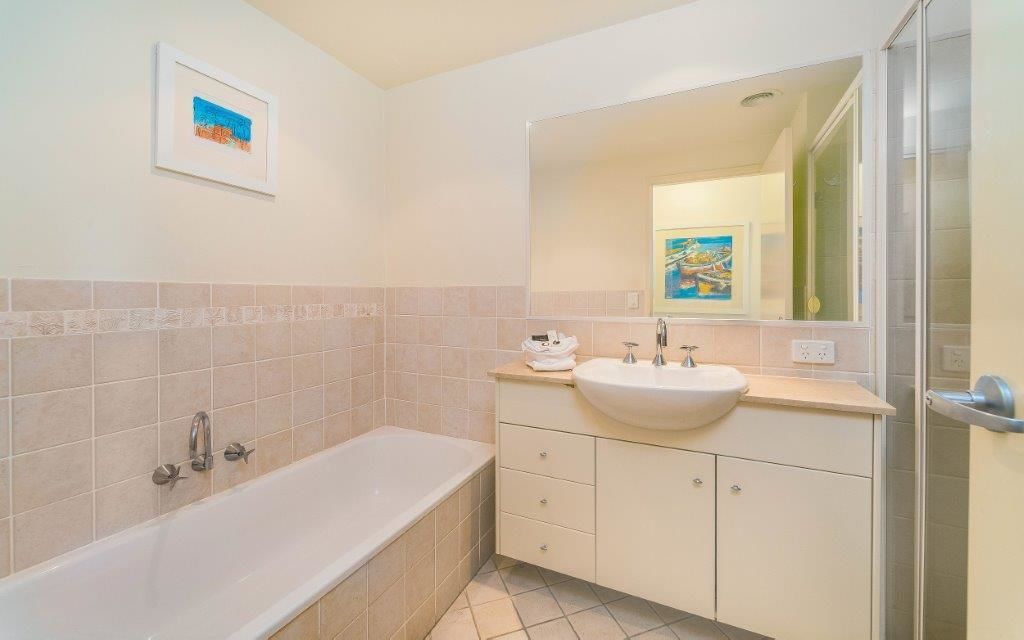 A bathroom with a bathtub, a sink, and a mirror.