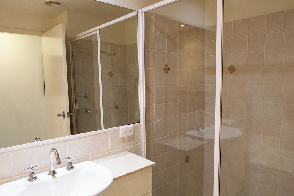 A bathroom with a double sink, a mirror, and a glass-enclosed shower area.