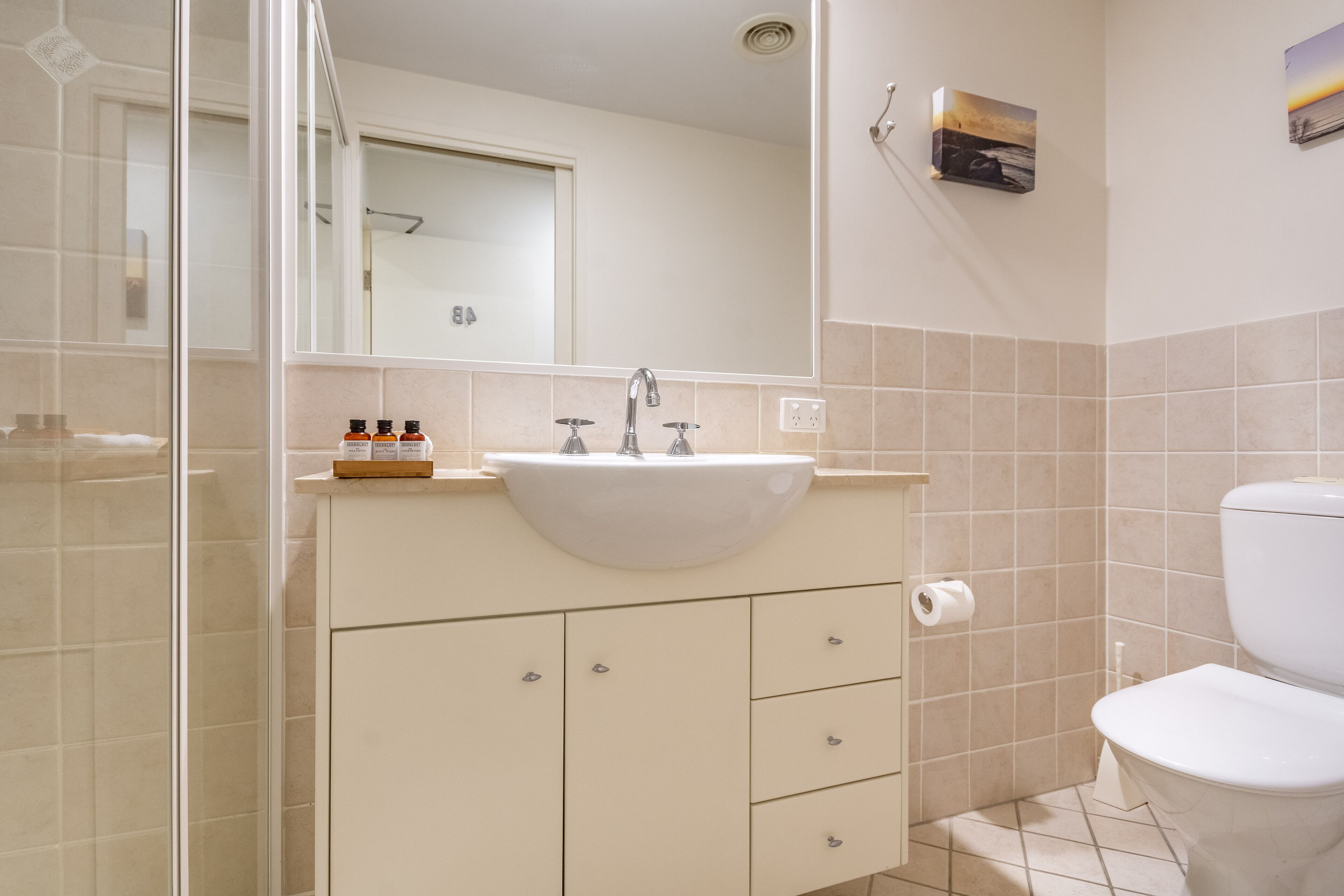Une salle de bain avec un lavabo blanc, un miroir et des toilettes.