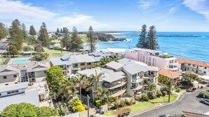 A coastal hotel with multiple buildings, a tennis court, and a view of the ocean. - The Cove Yamba (Yamba)