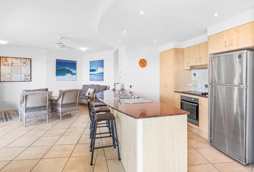 A modern kitchen with a central island, wooden cabinets, and stainless steel appliances.