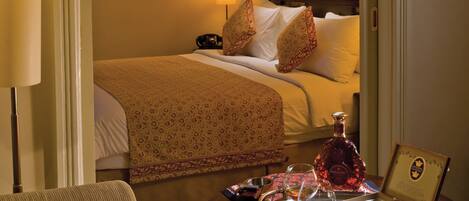 A hotel room with a bed, bedside table, lamp, and a decorative tapestry.