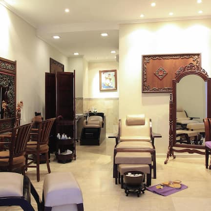 A traditional room with a sofa, chairs, a mirror, and a small table with a bowl and a candle.