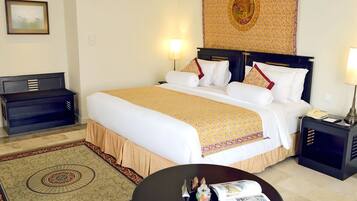 A hotel room with a large bed, bedside tables, a desk, and a patterned rug.
