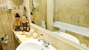 A bathroom with a large sink, a mirror, a hairdryer, and a bathtub.