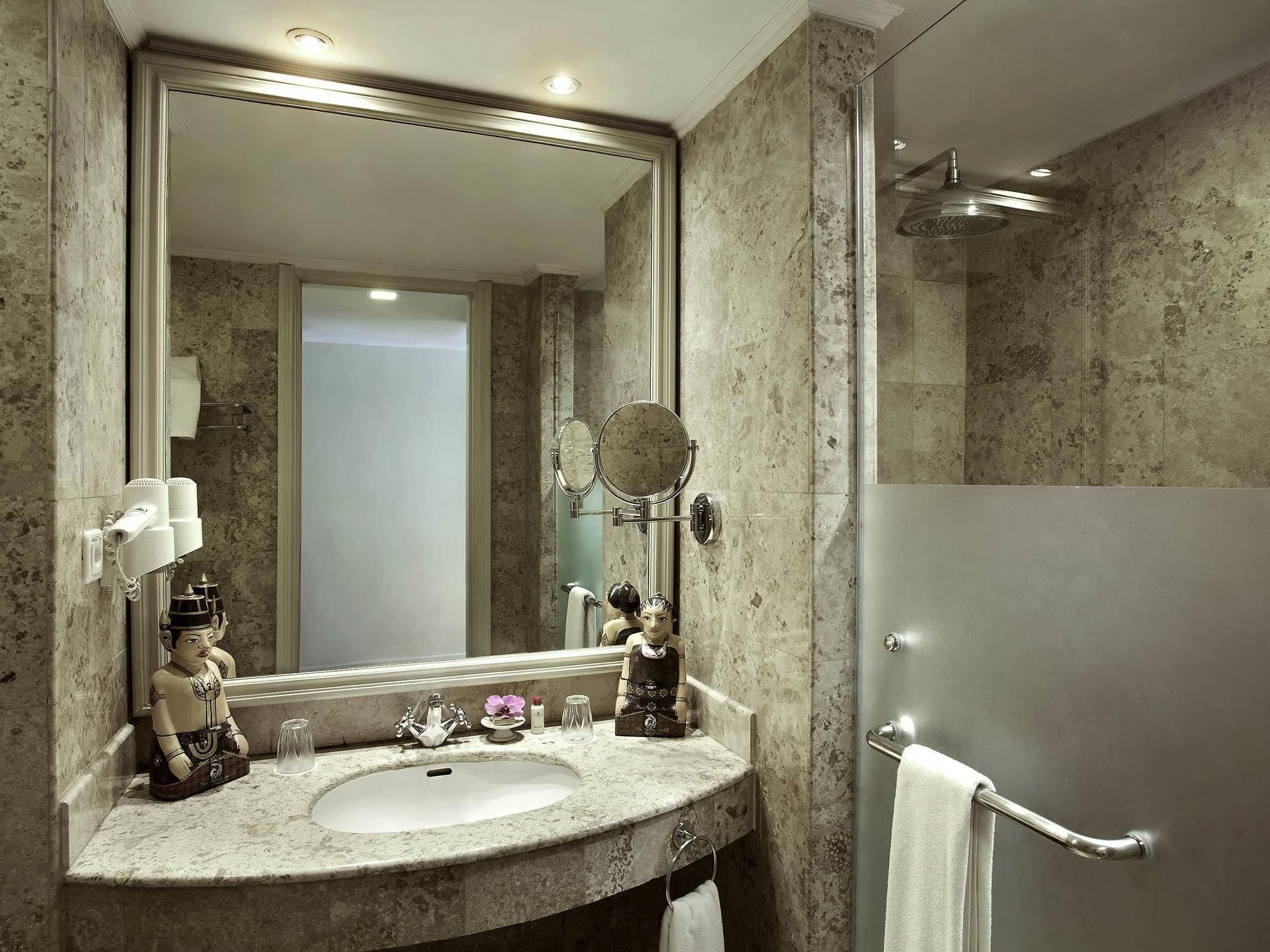 A bathroom with a marble sink, a large mirror, a shower, and a towel rack.