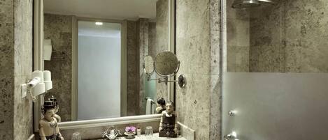 A bathroom with a marble sink, a large mirror, a shower, and a towel rack.