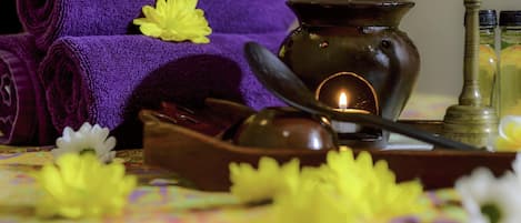Un entorno de spa con toallas enrolladas, una vela y aceites esenciales sobre una mesa.