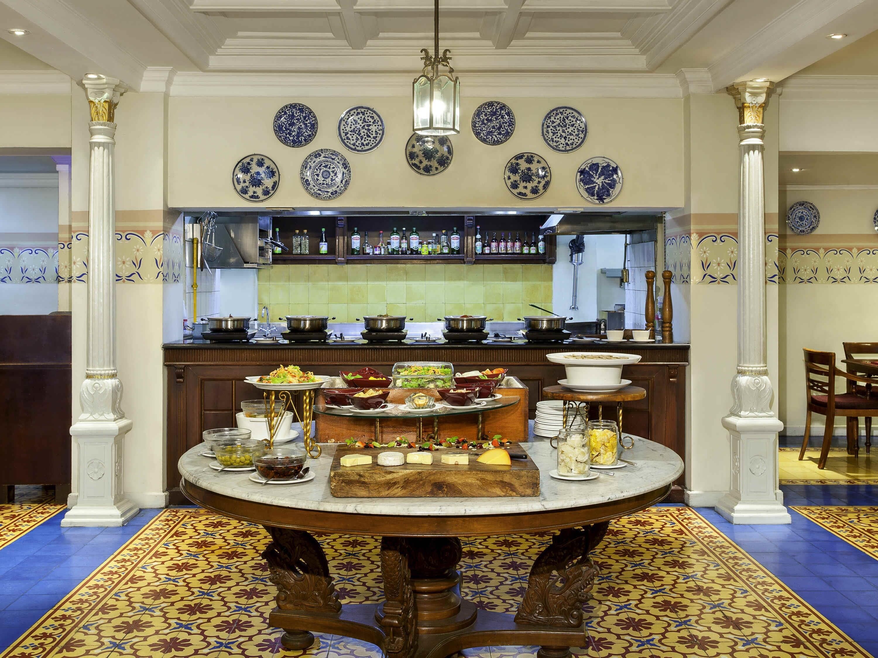 A dining area with a round table, a bar in the background, and decorative plates on the wall.